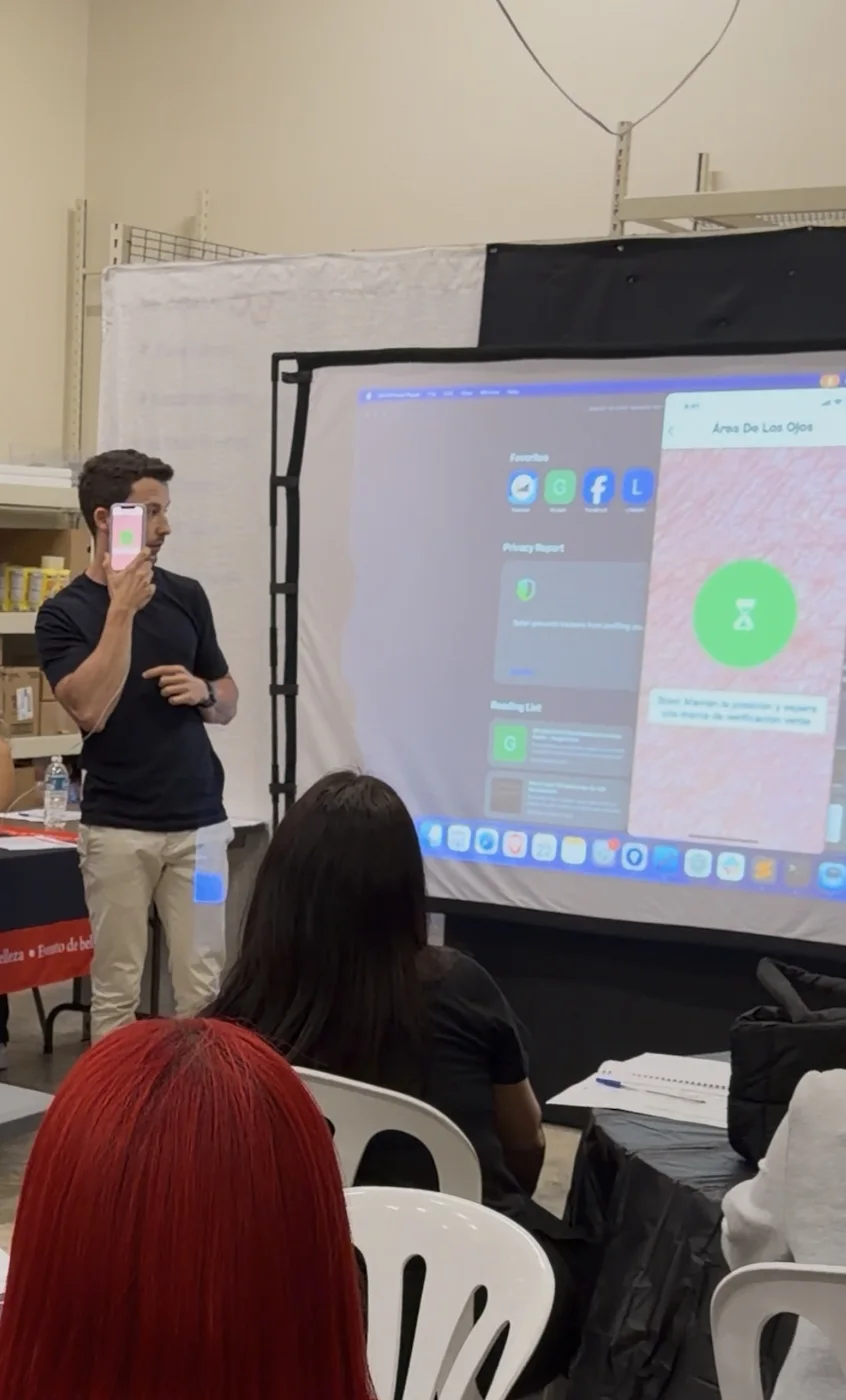Dan demonstrating a FitSkin scanner against his temple, with the app projected beside him