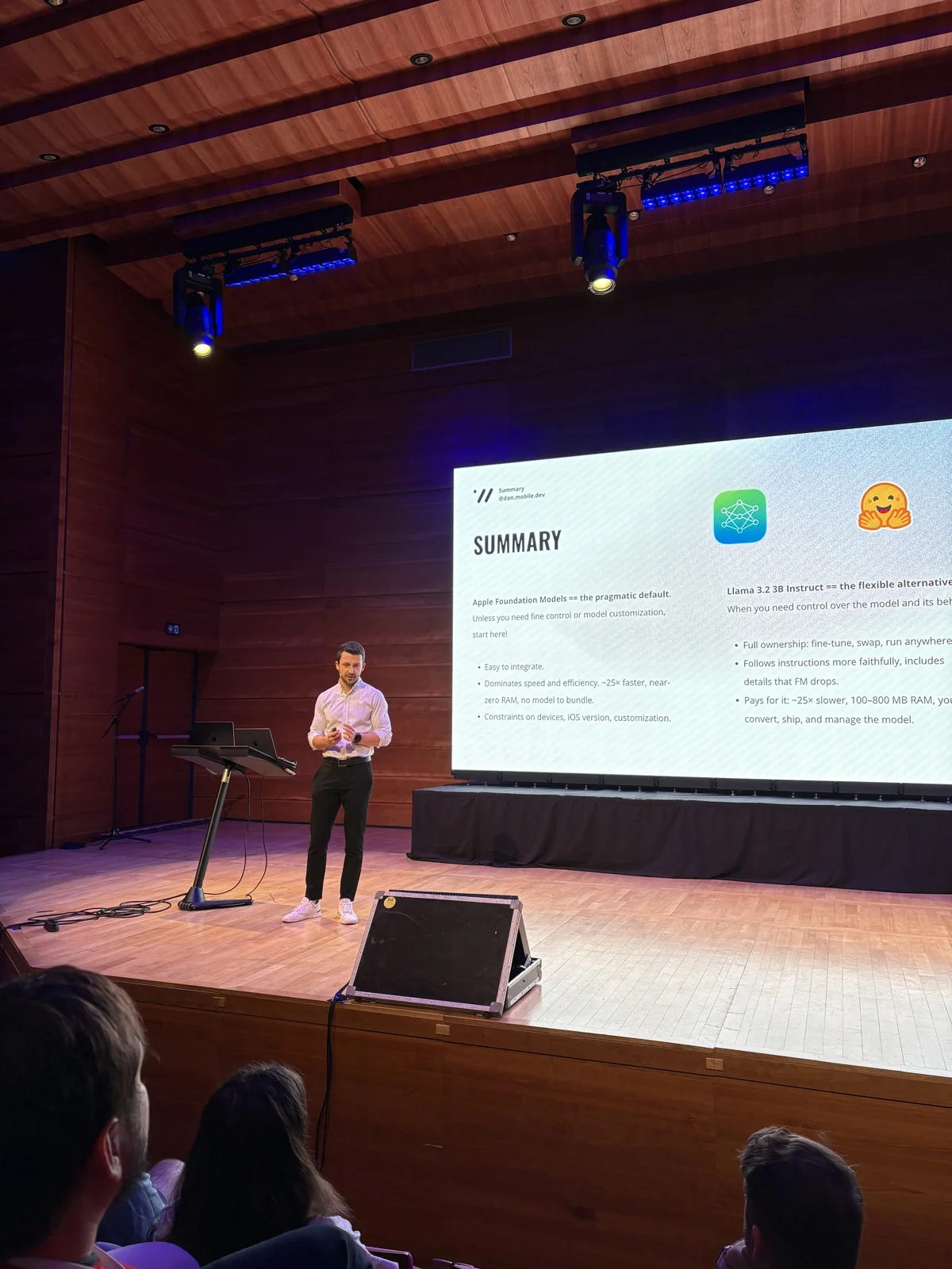 Dan on stage beside the comparison summary at iOSKonf 2026